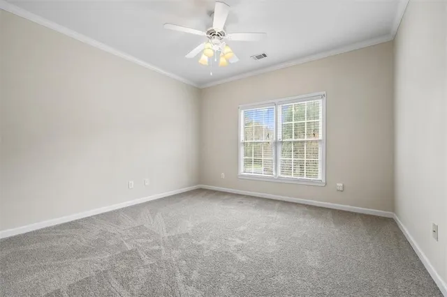 an empty room with chandelier fan and windows