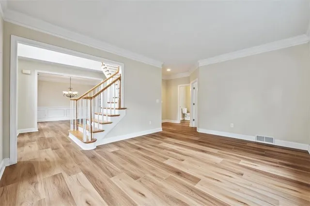 a view of empty room with stairs and wooden floor