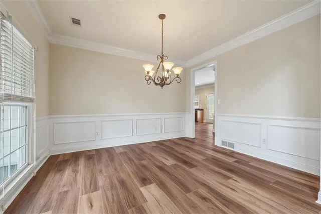 a view of a room with wooden floor chandelier and a window