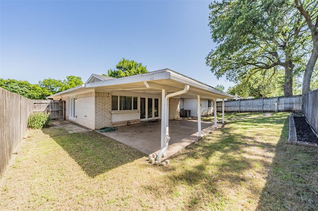 1301 Cedar Ridge Terrace Euless, TX 76039 - Photo 28 of 31 Expansive backyard featuring a covered patio, brick planter bed, and mature trees.