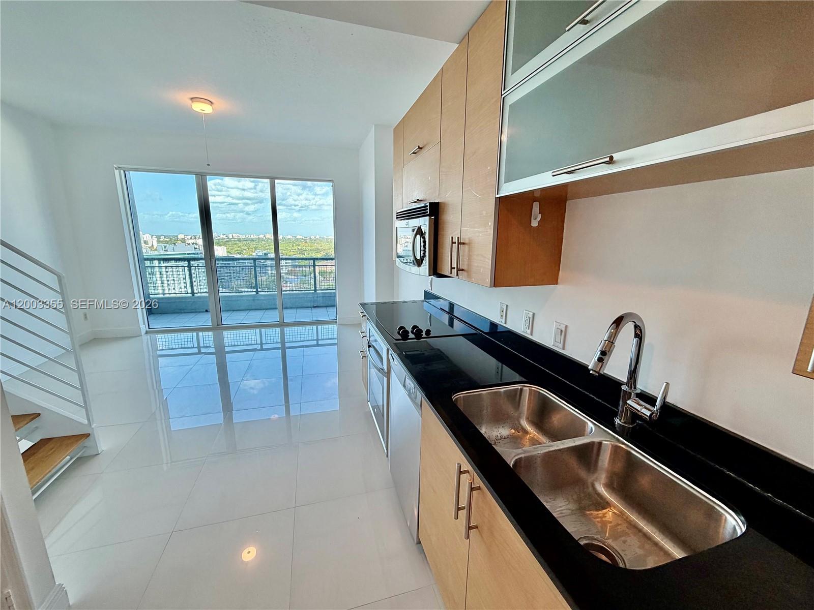 60 Southwest 13th Street, Unit 1605 Miami, FL 33130 - Photo 5 of 18 a kitchen with a sink and a stove top oven