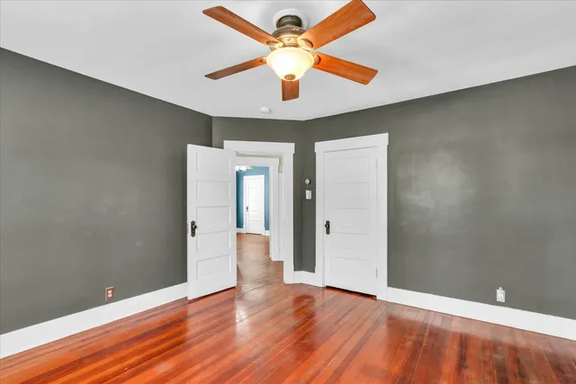 an empty room with wooden floor and a ceiling fan