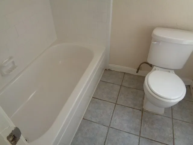a white toilet sitting next to a bath tub