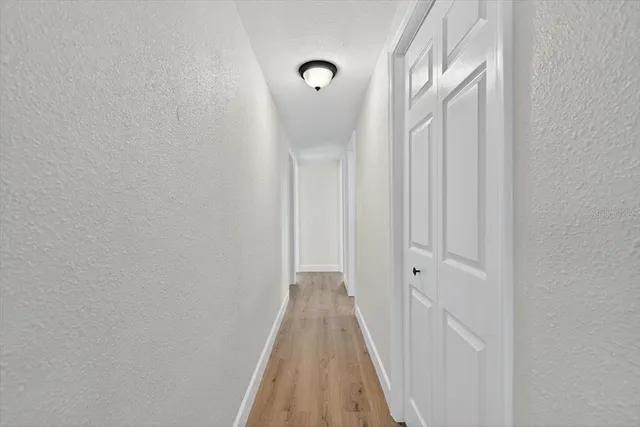 a view of a hallway with wooden floor and a window