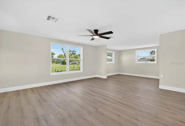 a view of an empty room with a window and wooden floor