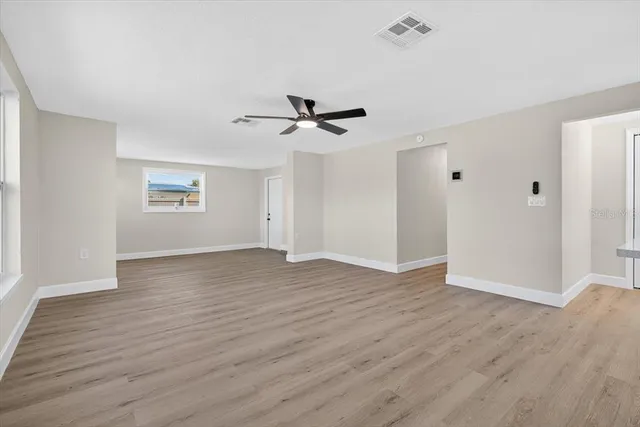 an empty room with wooden floor and ceiling fan