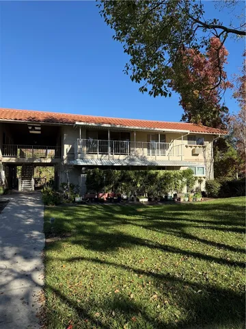 a view of a big house next to a big yard and large trees