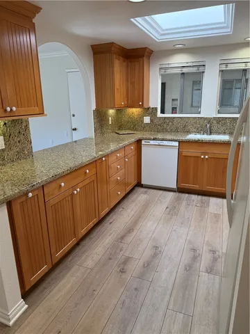 a large kitchen with granite countertop wooden cabinets a sink and dishwasher
