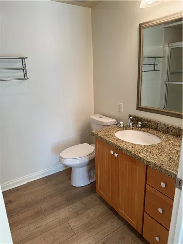 a bathroom with a granite countertop sink toilet and mirror