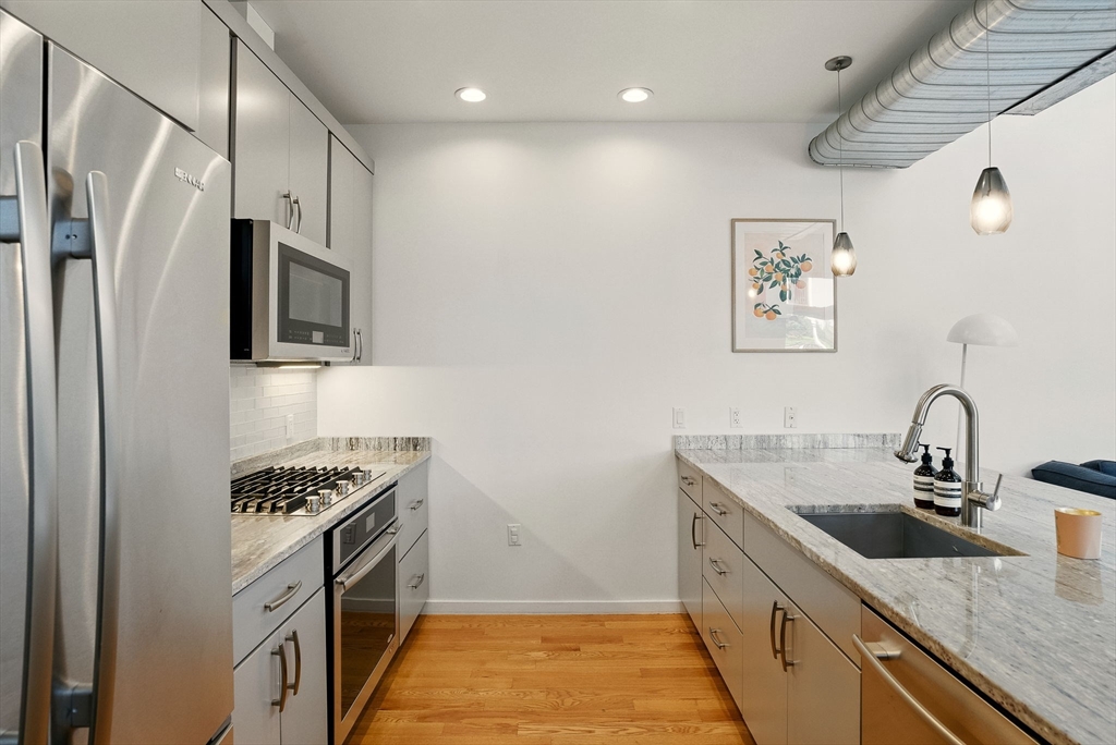 151 Sherman Street Cambridge, MA 02140 - Photo 11 of 35 a kitchen with stainless steel appliances granite countertop a sink stove and refrigerator