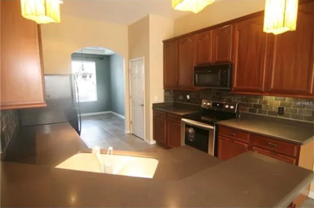 1518 Tally Circle Oviedo, FL 32765 - Photo 4 of 15 a kitchen with stainless steel appliances a stove a sink a microwave a refrigerator and cabinets