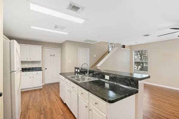 a kitchen with stainless steel appliances granite countertop a sink a stove and a wooden floors