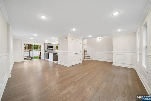 a view of an empty room with wooden floor and kitchen