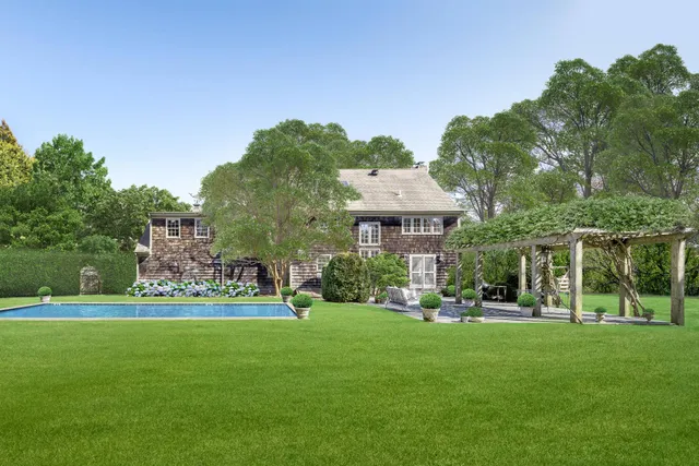 a view of a house with a big yard potted plants and large trees