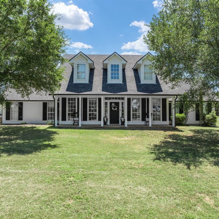 White brick exterior featuring a dark asphalt shingle roof and black shutters