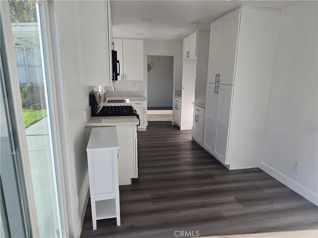a kitchen with wooden floor and electronic appliances
