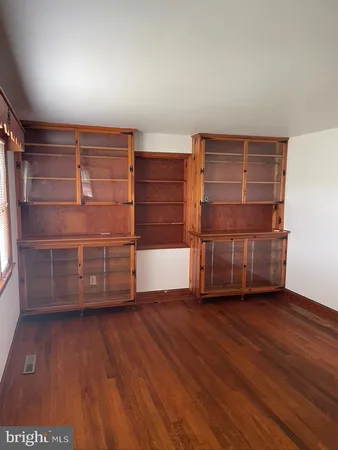 an empty room with wooden floor and cabinet