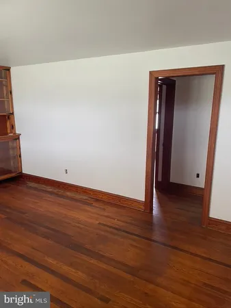 a view of an empty room with wooden floor and closet