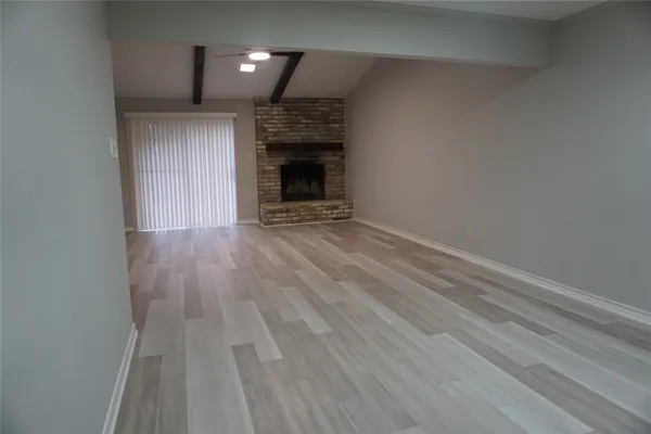 an empty room with wooden floor fireplace and windows