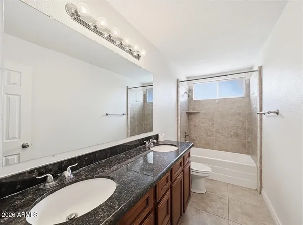 a bathroom with a granite countertop sink a mirror and a bathtub