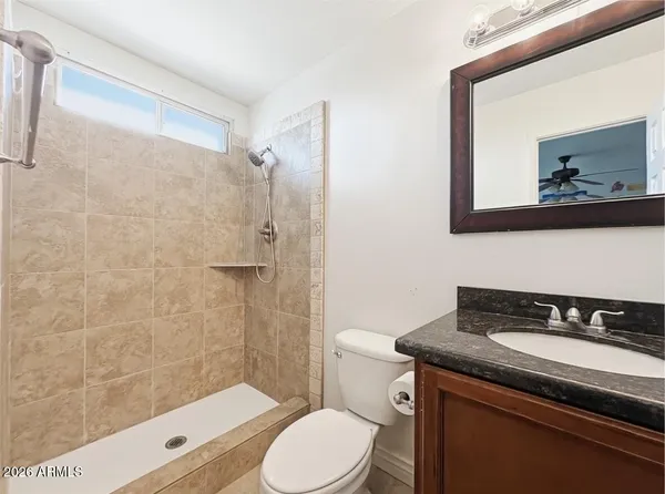 a bathroom with a granite countertop toilet sink and mirror