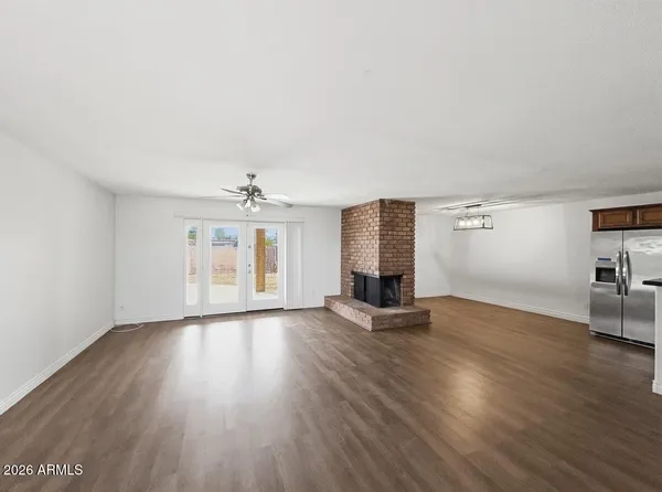 an empty room with wooden floor chandelier and windows