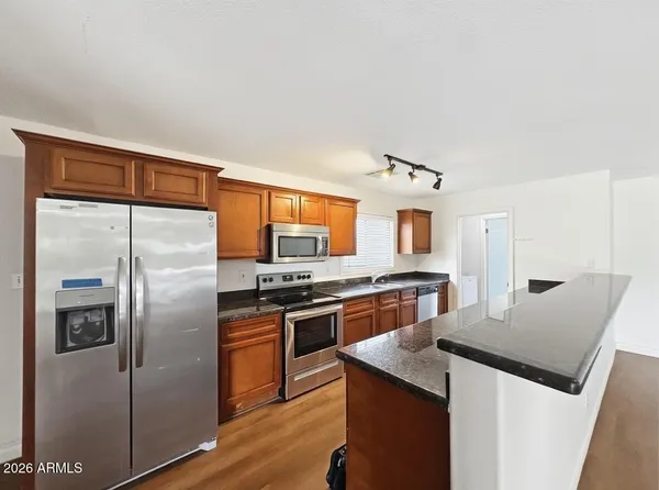 a kitchen with stainless steel appliances granite countertop a refrigerator a stove top oven a sink and dishwasher