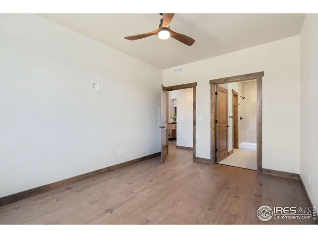an empty room with wooden floor a ceiling fan and a window