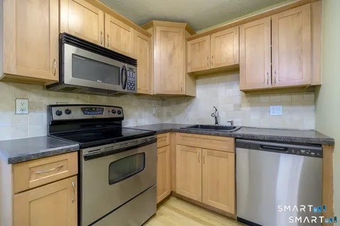 637 Cove Road, Unit A3 Stamford, CT 06902 - Photo 2 of 7 a kitchen with granite countertop a stove top oven microwave and cabinets