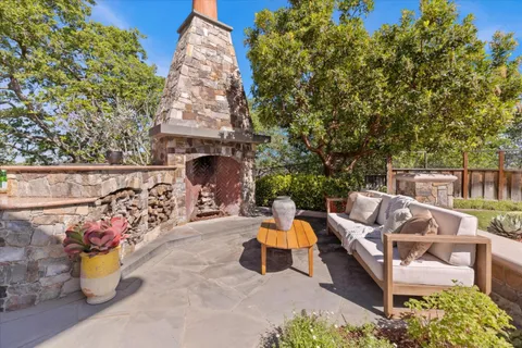 a view of a patio with couches and table and chairs with wooden fence and plants