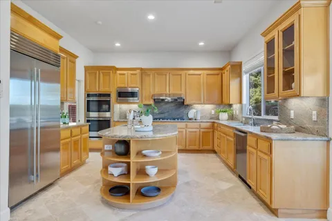 a kitchen with stainless steel appliances granite countertop a stove a sink and a refrigerator
