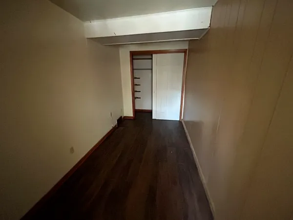 a view of a hallway with wooden floor and a wall