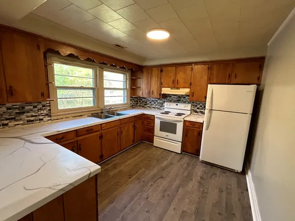 a kitchen with wooden floors sink stainless steel appliances and window