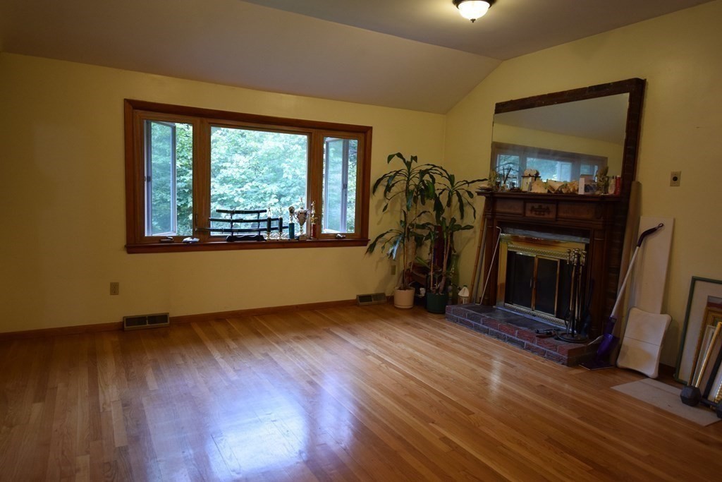 69 Deerfield Road Sharon, MA 02067 - Photo 4 of 12 an empty room with wooden floor fireplace and windows