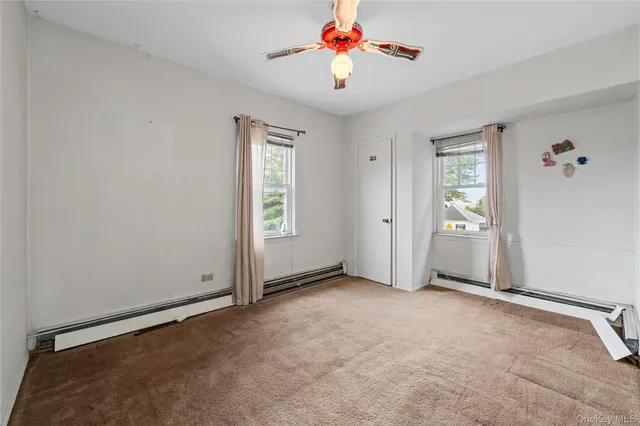 an empty room with a chandelier fan and windows