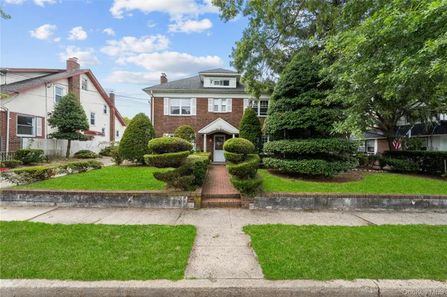 a view of a brick house with a yard and plants