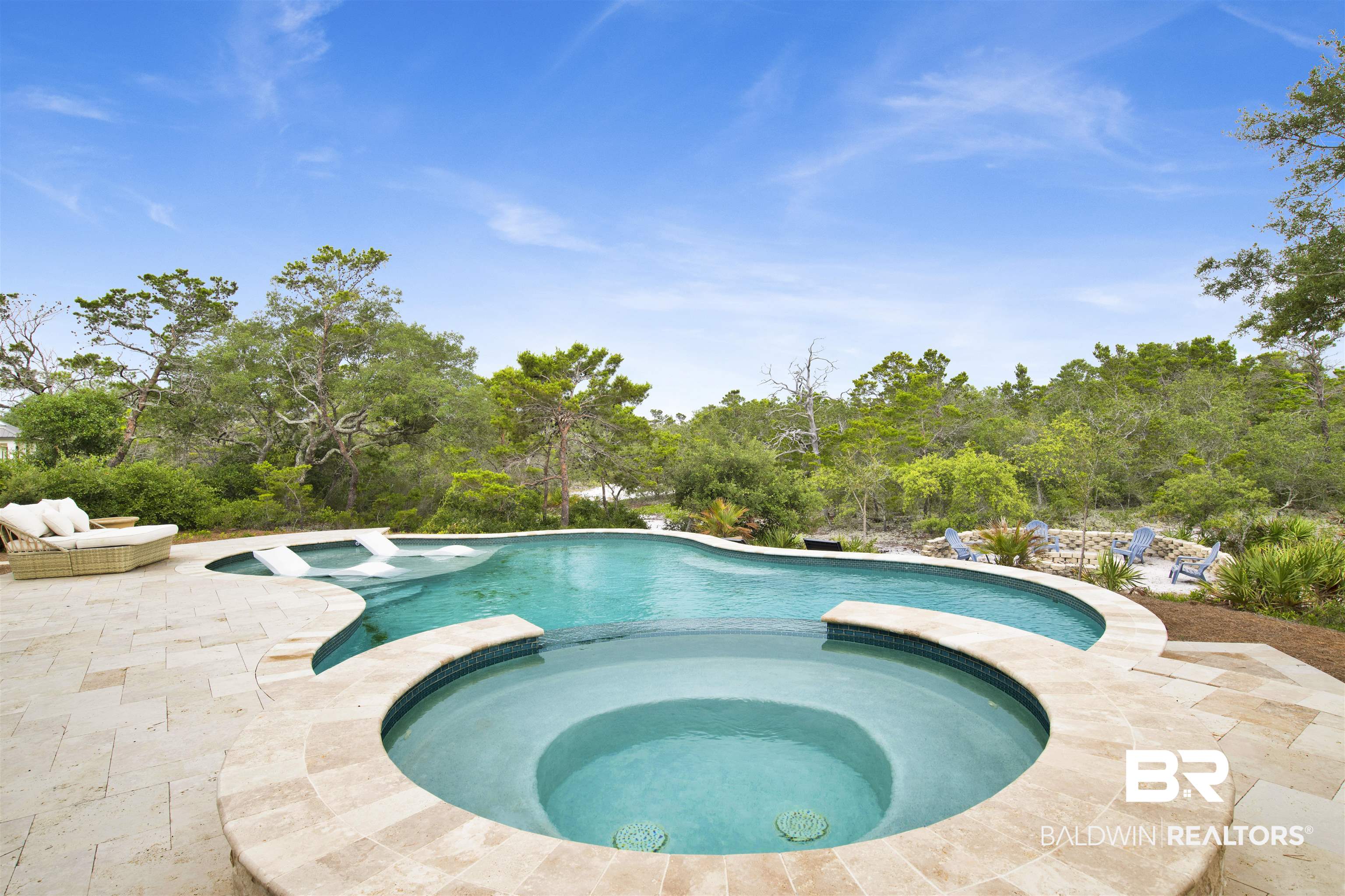 30351 River Road Orange Beach, AL 36561 - Photo 7 of 44 Freeform pool and spa with integrated steps, surrounded by a natural stone paver deck