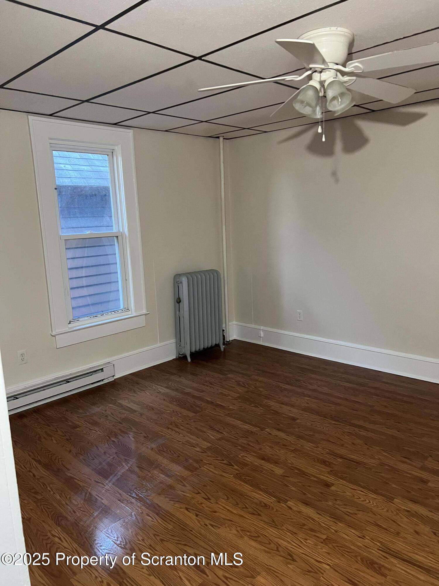 1330 Pittston Avenue, Unit 2N Scranton, PA 18505 - Photo 4 of 12 an empty room with wooden floor chandelier fan and windows