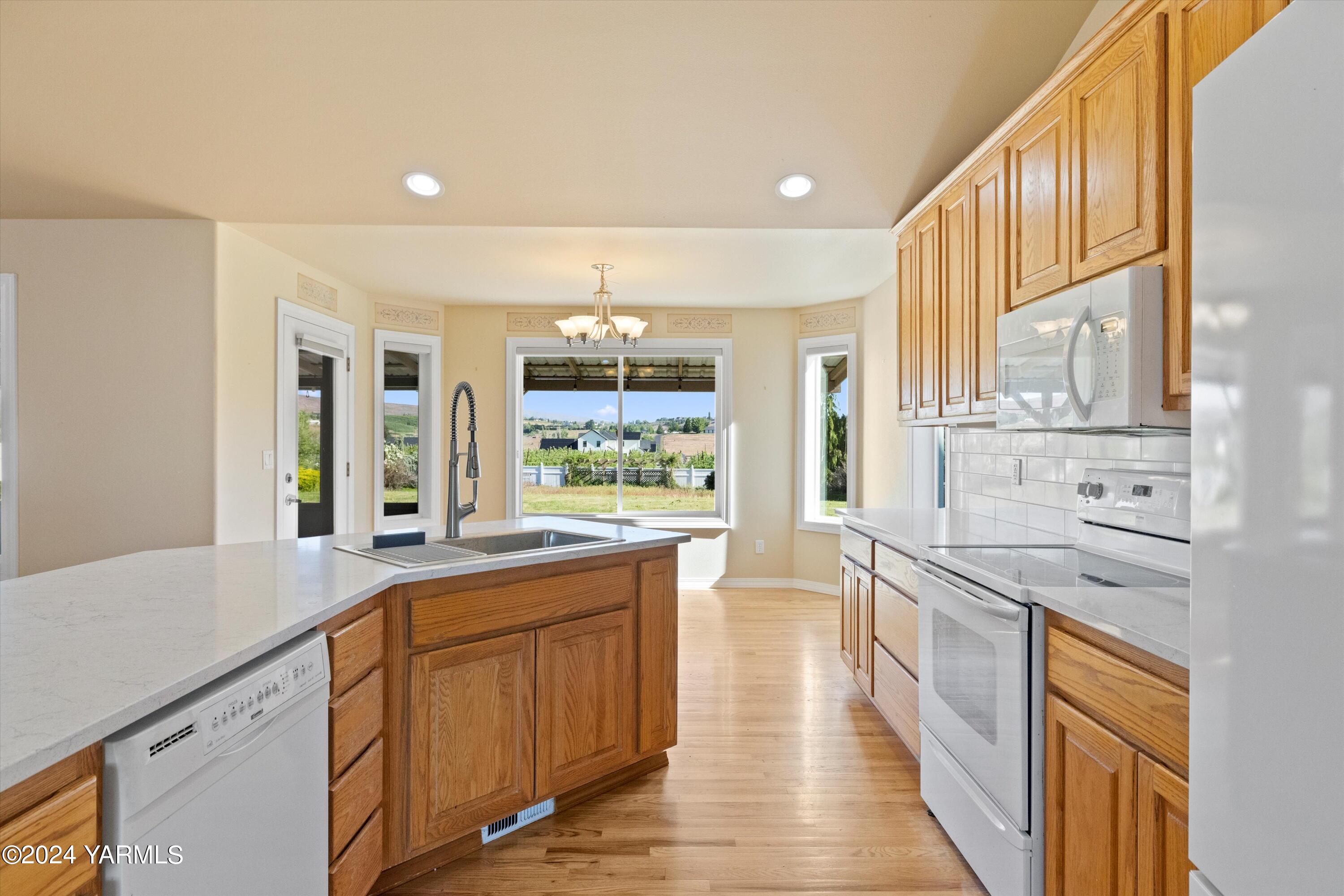 12555 West Barrett Road Yakima, WA 98908 - Photo 8 of 27 a kitchen with stainless steel appliances granite countertop a refrigerator a sink dishwasher a stove and white countertops with wooden floor