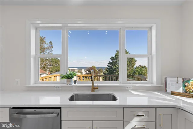 a kitchen with stainless steel appliances a stove a sink a refrigerator white cabinets and couches with wooden floor