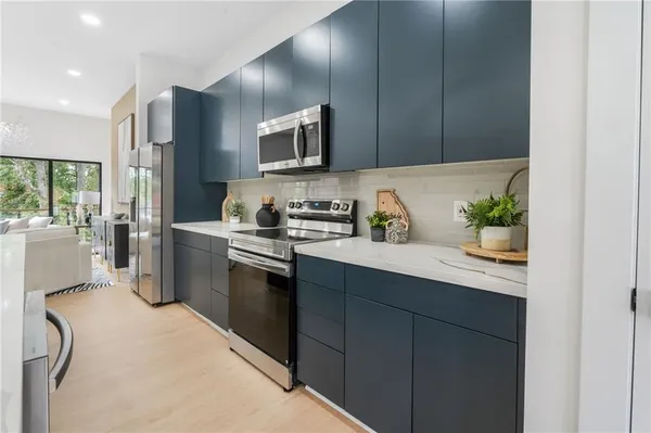 an open kitchen with kitchen island a stove a sink a refrigerator and windows