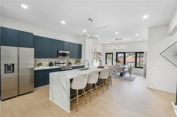 a large kitchen with kitchen island a sink a center island stainless steel appliances and cabinets