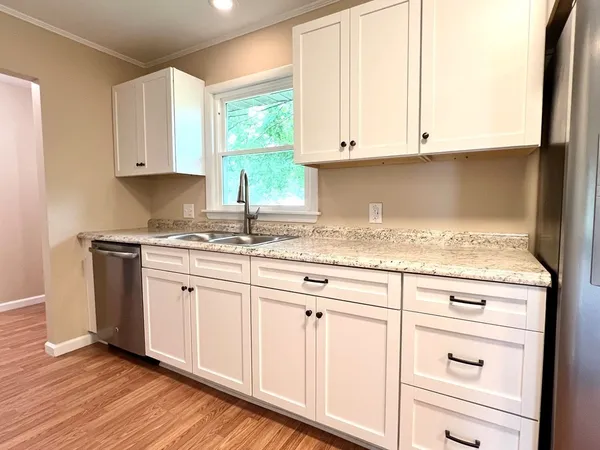 a kitchen with granite countertop white cabinets and a sink