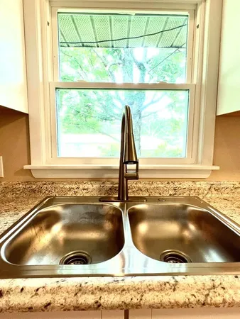 a bathroom with a granite countertop sink and a window