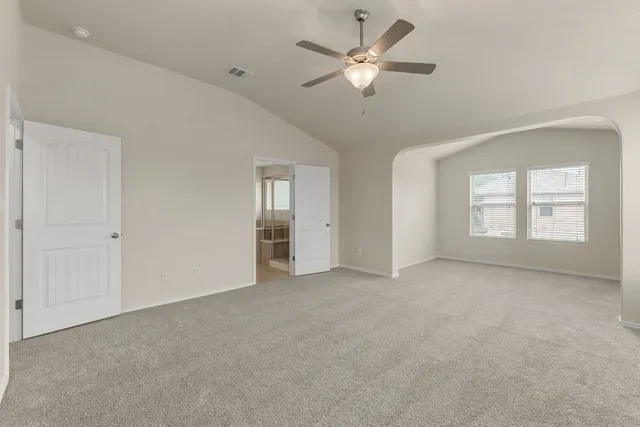 an empty room with chandelier fan and windows