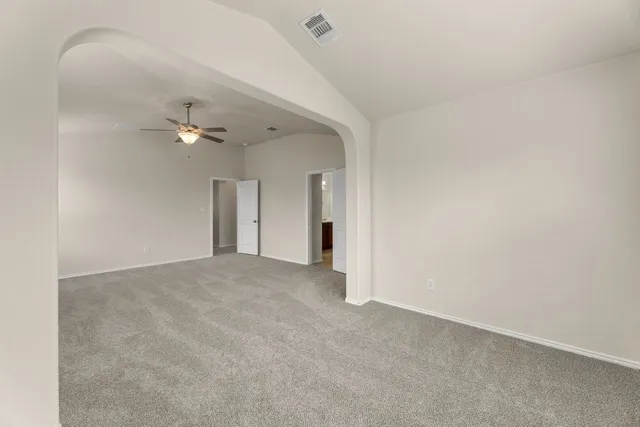 a view of an empty room with a chandelier fan