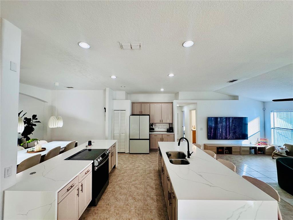 3840 Marietta Way St. Cloud, FL 34772 - Photo 27 of 44 a large white kitchen with stainless steel appliances kitchen island a stove a sink dishwasher and a refrigerator with wooden floor