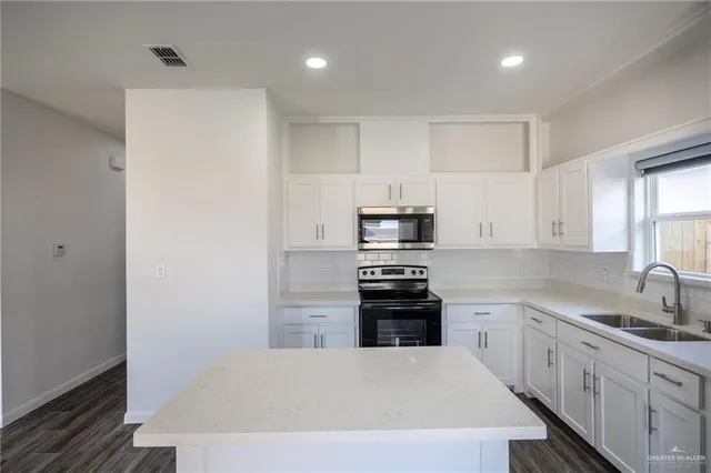 a kitchen with stainless steel appliances a stove refrigerator sink and white cabinets
