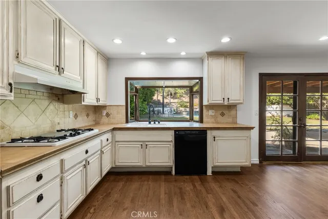a large kitchen with stainless steel appliances granite countertop a stove a sink and white cabinets