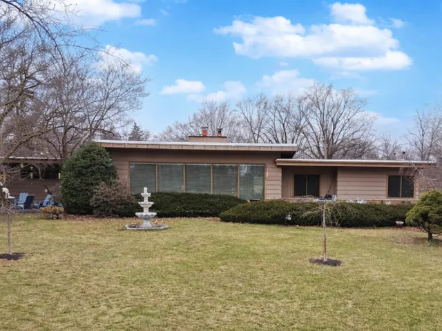 a view of a big house with a big yard and large trees